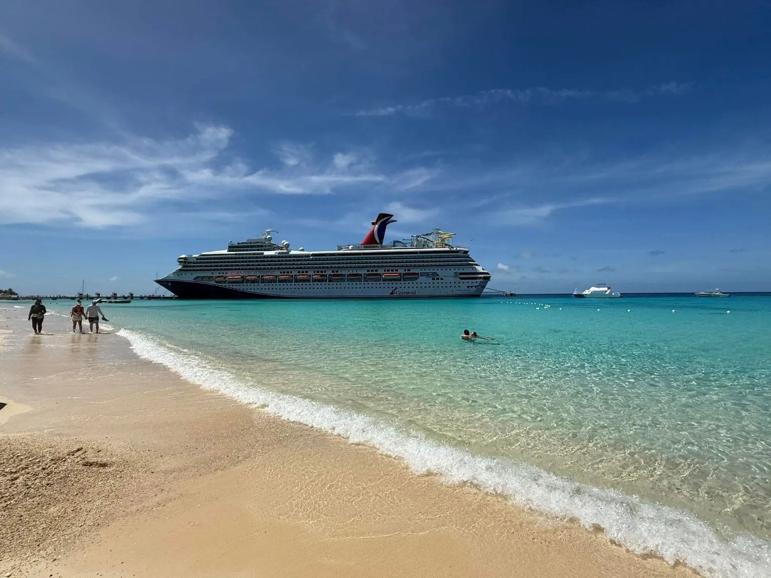 Carnival cruise ship beside a sandy beach and clear turquoise water, photographed on Ashley’s family vacation