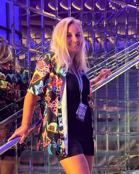 Ashley smiling on a cruise ship’s glass staircase