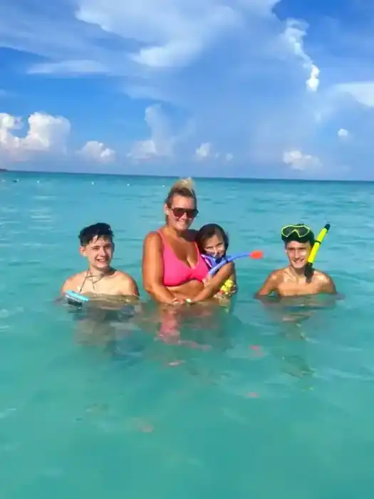 Ashley with her children snorkeling during a family cruise beach day
